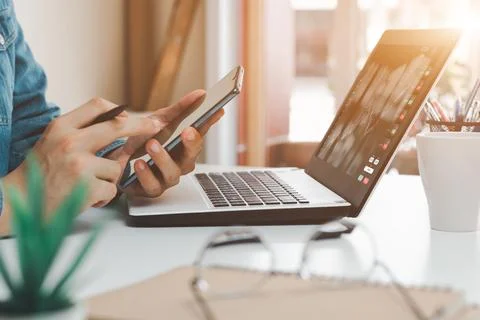 Work using mobile phone typing computer mobile chat laptop contact us at work Stock Photos