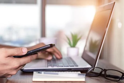 Work using mobile phone typing computer mobile chat laptop contact us at work Stock Photos