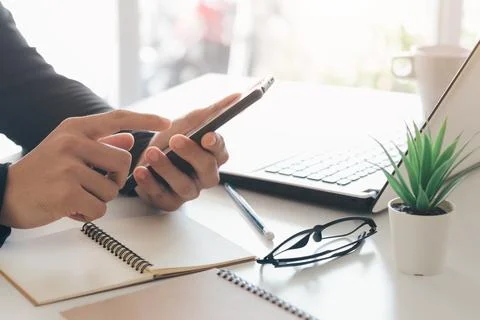 Work using mobile phone typing computer mobile chat laptop contact us at wo.. Stock Photos