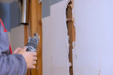 Work on wall repair in home with tool being used for cutting drywall Stock Photos