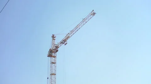 The work of a yellow construction crane. Building on clear blue sky background Video stock 155954609
