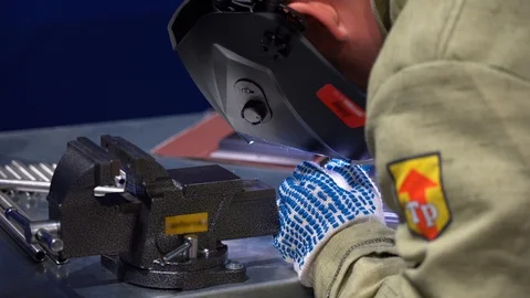 At workbench unrecognizable male welder working, welds metal tube close up view  Stock Footage 126356438