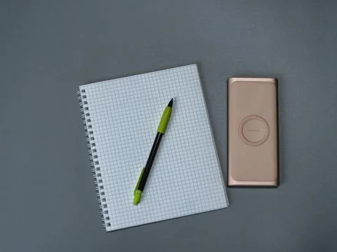 A workbook in a cage, a pen and wireless power bank Stock Photos