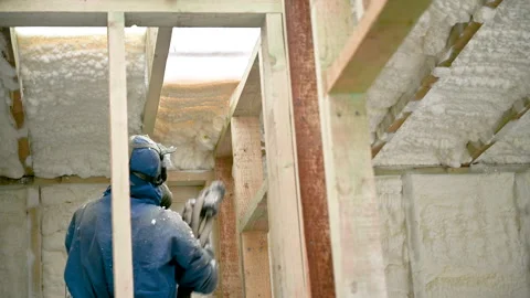 Worker adds expanding insulation foam to framed wall during renovation Stock Footage 346725416