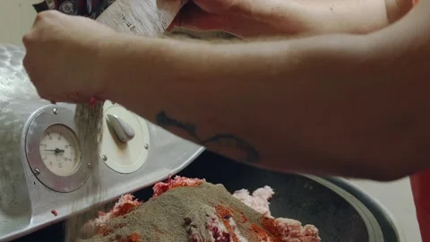 Worker adds a mixture of herbs and spices into minced meat for producing Stockbeeldmateriaal 152655868