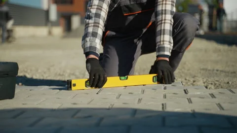 Worker Adjusting Paving Stones with Level Stock Footage 297791109