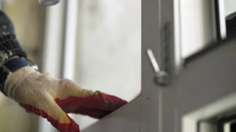 Worker adjusting plastic window frame installation Stock Footage 323870826
