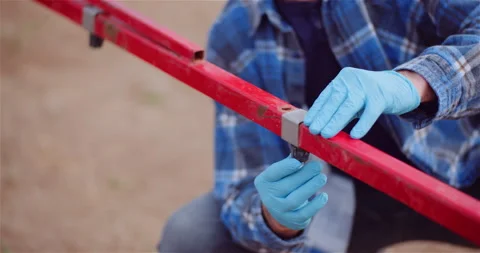 Worker adjusting a red metal frame outdoors 動画素材 336498090