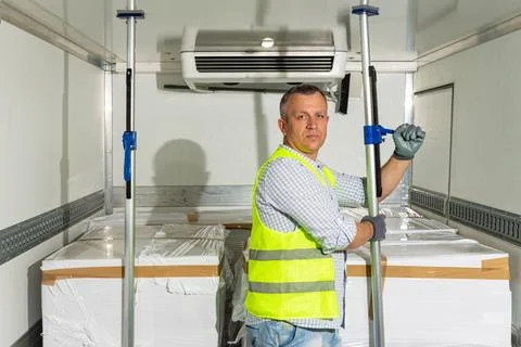 Worker adjusting temperature in refrigerated cargo box Stock Photos