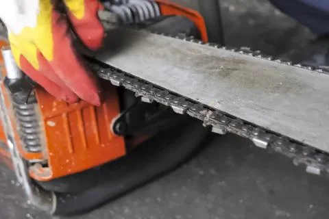 Worker adjusts the chain on the chainsaw bar. Stock Photos