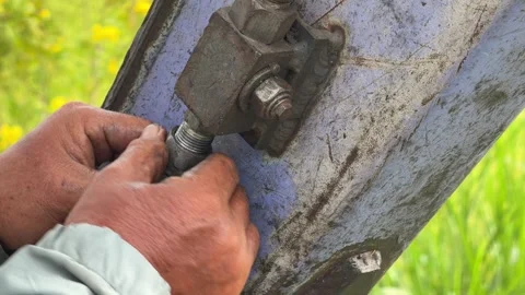 A worker adjusts a fastening element on a hydraulic metal joint of an excavator Stock Footage 332029709