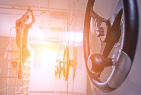 A worker adjusts gym equipment while standing on a ladder in a fitness center Foto stock