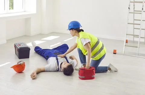 Worker Administers First Aid with Workplace Kit to Colleague After Accident Foto stock