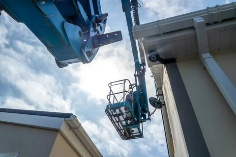 Worker on a aerial access platform, cherry picker, cleaning house Stock Photos