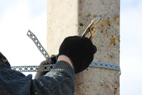 Worker affixes a chrome clamp to a post for hanging a road sign Stock Photos