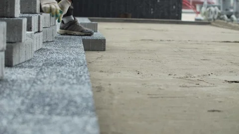 Worker aligning paving stones along concrete curb Stock Footage 326064655