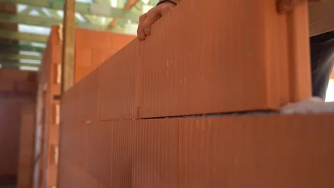 Worker aligns ceramic blocks while constructing wall in unfinished house Stock Footage 311418586