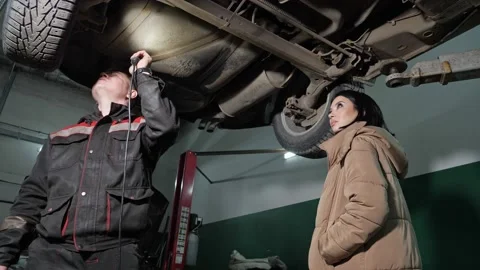 Worker and client with flashlight check automobile bottom Stock Footage 149810554