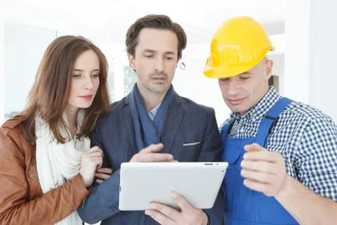 Worker and couple at construction site Stock Photos