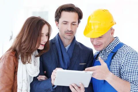 Worker and couple using tablet pc Stock Photos