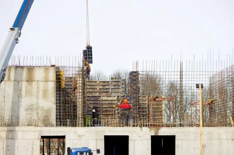 The worker and the crane operator unload the car with reinforced concrete wal Stock Photos