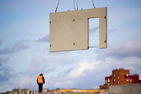 The worker and the crane operator unload the car with reinforced concrete wal Stock Photos