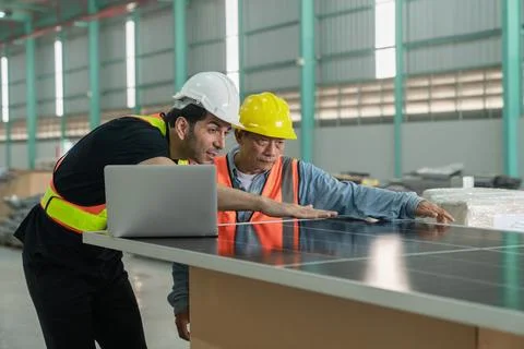 Worker and engineer discussing over solar panel in warehouse. Foto stock