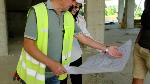 Worker and engineers look at building layout analysing drawing Video stock 317609398