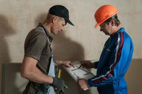 Worker and foreman discuss the scheme plasterboard ceiling Stock Photos