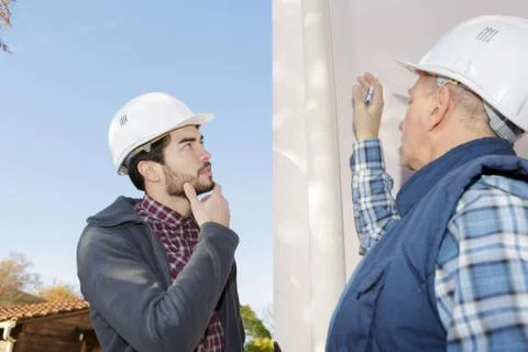 Worker and his apprentice inspecting a gutter prior to work Stock Photos