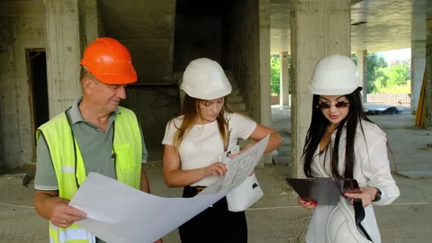 Worker and lady experts discussing blueprint of building Stock Footage 317609820