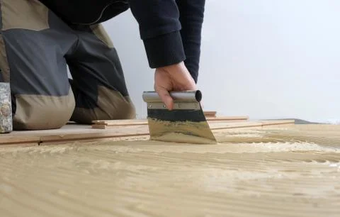 Worker applied adhesive for parquet Stock Photos