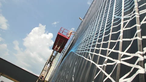 Worker applies abstract line pattern onto workshop facade Stock Footage 223938595