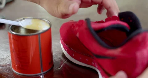 Worker applies adhesive glue to the inside of a damaged sneaker to prepare. Stock Footage 313495574