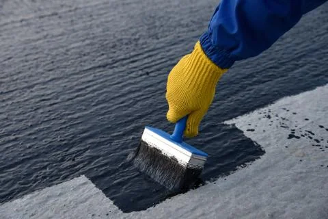 Worker applies bitumen mastic on the foundation Stock Photos