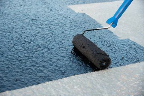 Worker applies bitumen mastic on the foundation Foto stock
