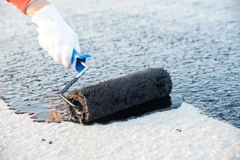 Worker applies bitumen mastic on the foundation Stock Photos
