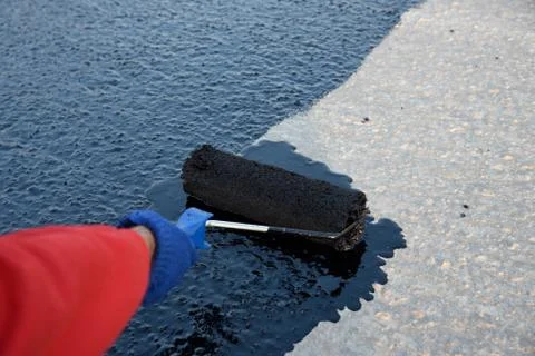 Worker applies bitumen mastic on the foundation Stock Photos