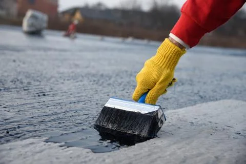 Worker applies bitumen mastic on the foundation Foto stock