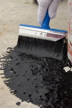 Worker applies bitumen mastic on the foundation Foto stock