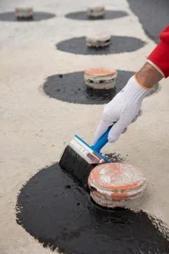 Worker applies bitumen mastic on the foundation Foto stock