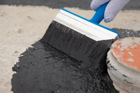 Worker applies bitumen mastic on the foundation Stock Photos