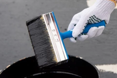 Worker applies bitumen mastic on the foundation Stock Photos