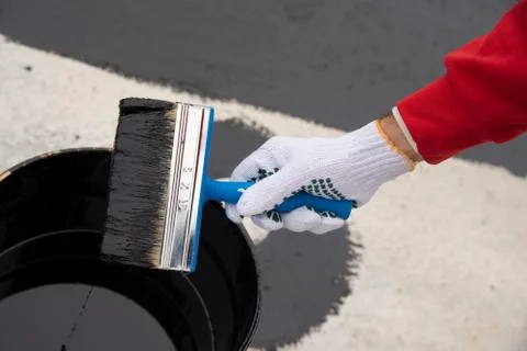 Worker applies bitumen mastic on the foundation Stock Photos