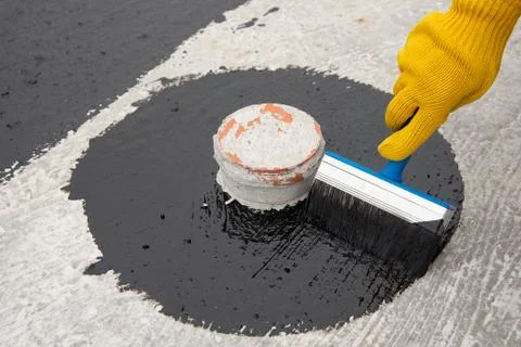 Worker applies bitumen mastic on the foundation Foto stock