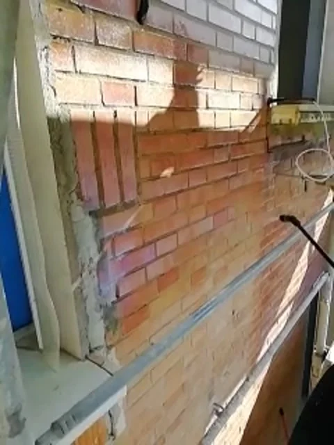 Worker applies a coat of spray primer to an exterior brick wall Video stock 330466110