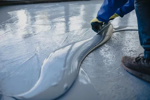 The worker applies gray epoxy resin to the new floor Stock Photos