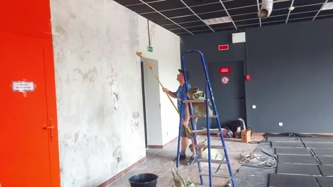 Worker applies paint to a wall in a room with new design plan during afternoon h Video stock 325053258