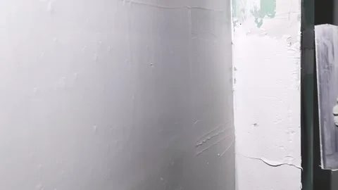 Worker applies plaster to wall in construction area during the day Stock Footage 326376301