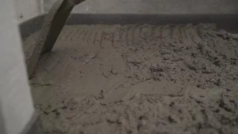 The worker applies the solution with a shovel to level the concrete floor. Fi Stock Photos